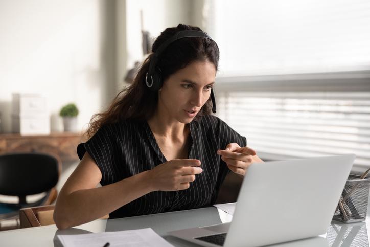 Concentrated female in headset sit by pc support client remotely